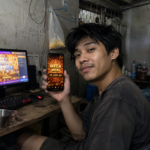 ผู้ใช้งาน TUNDER24HR ถือมือถือแสดง Mega Win 25,600 พร้อมเกมสล็อตบนคอมพิวเตอร์