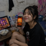 ผู้ใช้งาน TUNDER24HR ถือมือถือแสดง Mega Win 22,450 พร้อมเกมสล็อตบนคอมพิวเตอร์